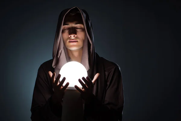 Junger Zauberer mit Kristallkugel im dunklen Raum — Stockfoto