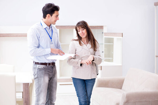Salesman explaining to woman customer at furniture store