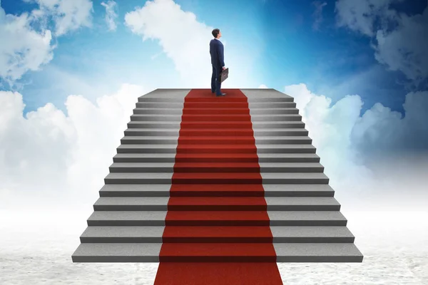 Joven hombre de negocios subiendo escaleras y alfombra roja en el cielo — Foto de Stock