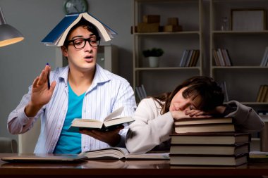 İki öğrenci geç saatlere kadar çalışıp sınavlara hazırlanıyor.