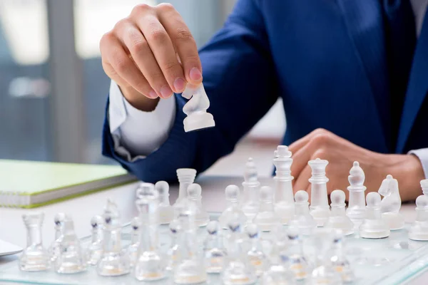 Молодой бизнесмен играет в стеклянные шахматы в офисе — стоковое фото