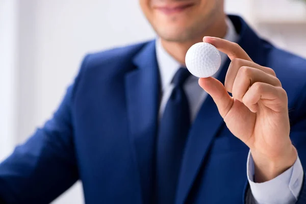 Young businessman with golf ball working in office — Stock Photo, Image