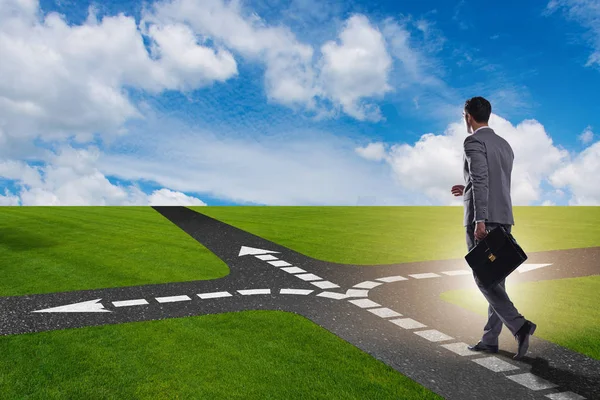 Young businessman at crossroads in uncertainty concept — Stock Photo, Image