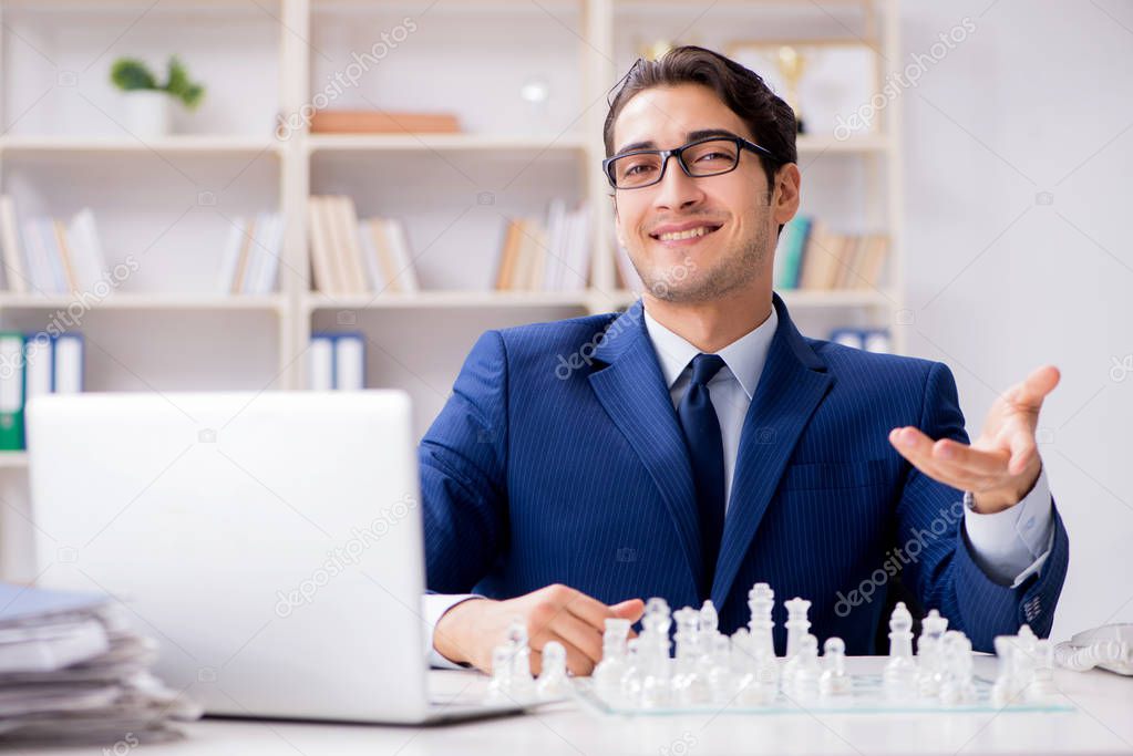 Young businessman playing glass chess in office