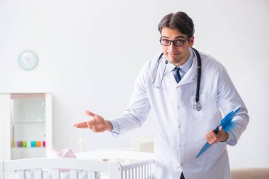 Erkek çocuk doktoru bebek yatağının yanında muayene etmeye hazırlanıyor.