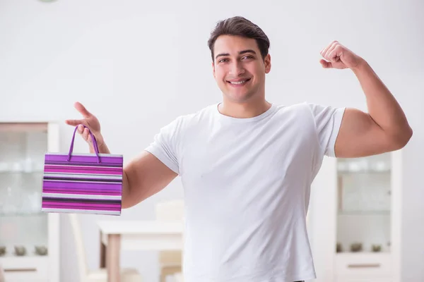 Jongeman met cadeau tas thuis voorbereiden verrassing voor vrouw — Stockfoto