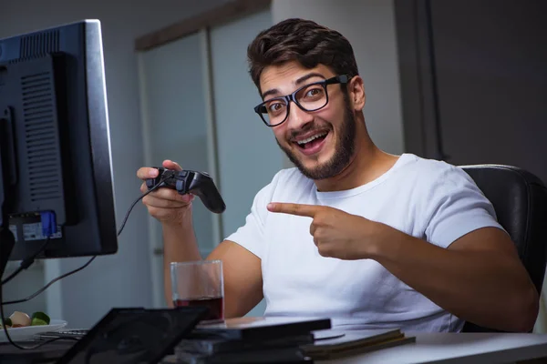 Jovem jogando jogos longas horas atrasado no escritório — Fotografia de Stock