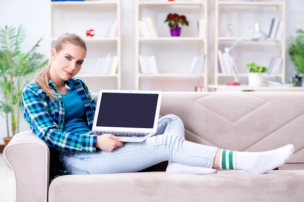 Estudante feminina sentada no sofá com laptop — Fotografia de Stock