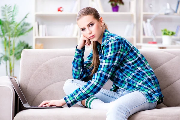 Kvinnlig student sitter i soffan med laptop — Stockfoto