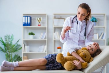 Kadın doktor oyuncak ayıyla küçük tatlı kızı muayene ediyor.
