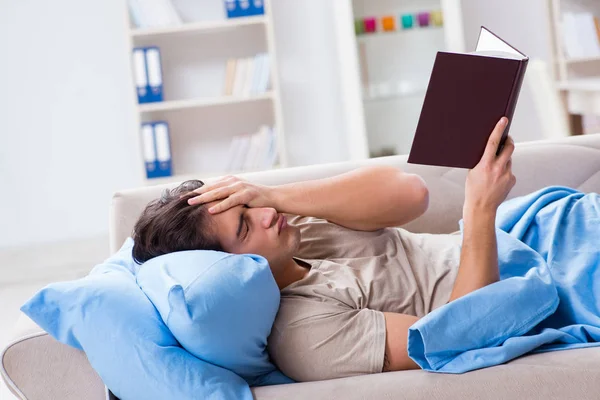 Jovem estudante se preparando para exames universitários na cama com livro — Fotografia de Stock