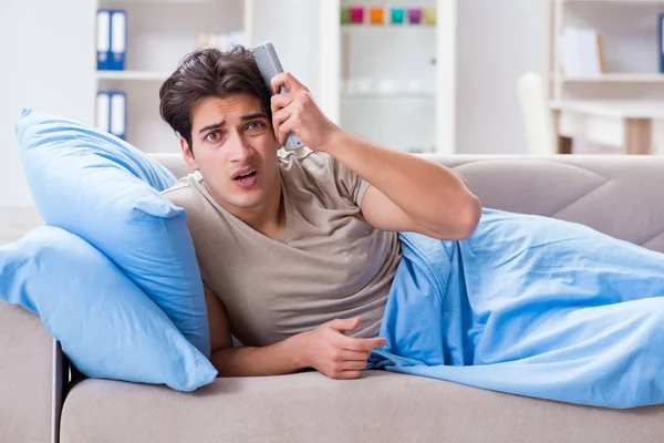 Muž sleduje televizi z postele drží dálkové ovládání — Stock fotografie