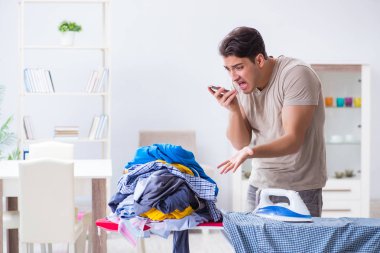 Genç adam evde çamaşır ütülüyor.