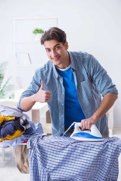 Jovem marido fazendo roupas de engomar em casa — Fotografia de Stock