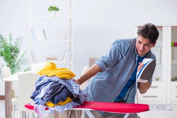 Joven marido haciendo planchado de ropa en casa — Foto de Stock