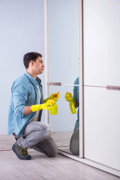 Young man cleaning mirror at home hotel — Stock Photo, Image