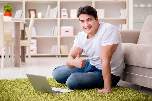 Uomo che lavora sul computer portatile a casa sul pavimento del tappeto — Foto Stock