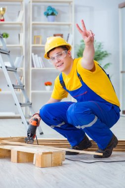 Ahşap palet montajı yapan genç adam.