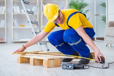 Ahşap palet montajı yapan genç adam.