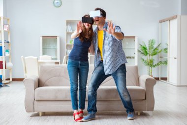 Genç bir aile sanal gerçeklik gözlükleriyle oyun oynuyor.