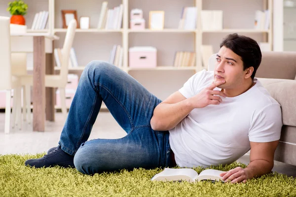 Adam evde yerde kitap okuyor. — Stok fotoğraf