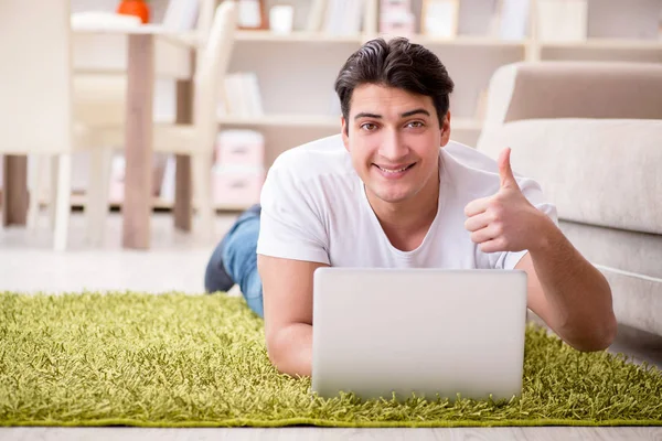 Uomo che lavora sul computer portatile a casa sul pavimento del tappeto — Foto Stock