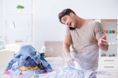 Dikkatsiz koca ütü yaparken giysilerini yakıyor.