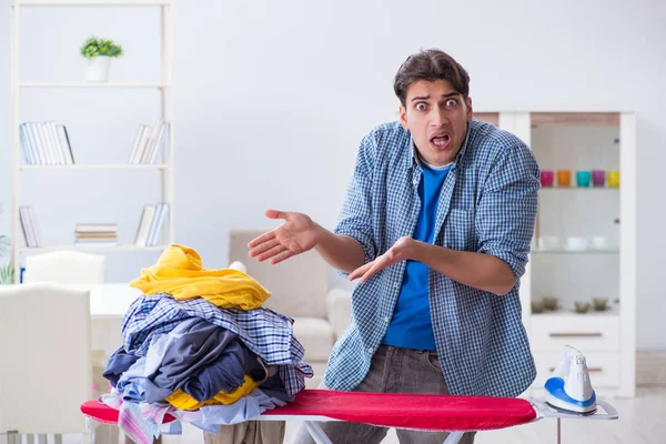 Joven marido haciendo planchado de ropa en casa — Foto de Stock