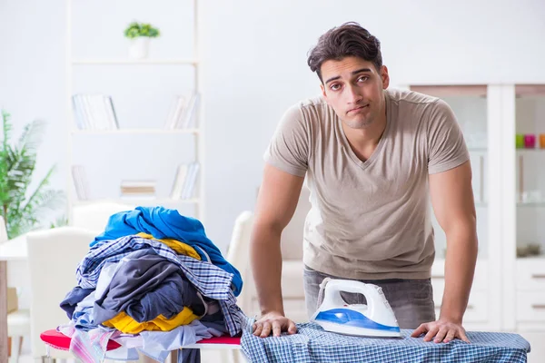 Молодой человек муж гладит одежду дома — стоковое фото