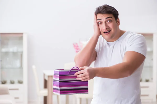 Jovem com saco de presente em casa preparando surpresa para a esposa — Fotografia de Stock