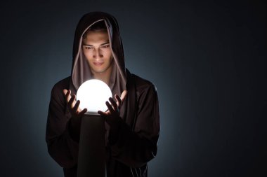 Karanlık odada kristal küreli genç büyücü