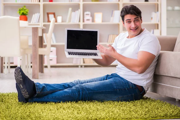 Uomo che lavora sul computer portatile a casa sul pavimento del tappeto — Foto Stock