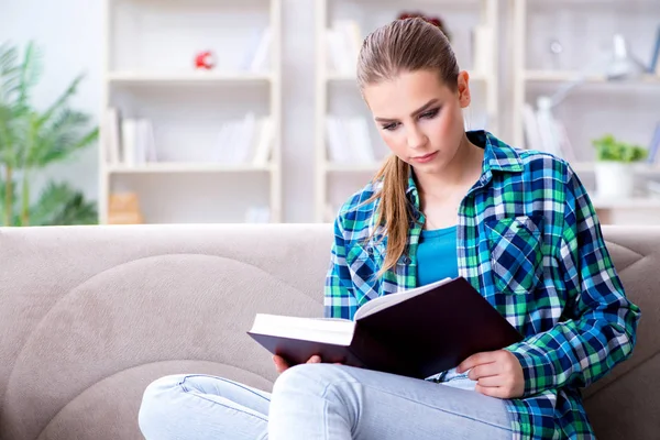Estudiante leyendo el libro sentada en el sofá — Foto de Stock