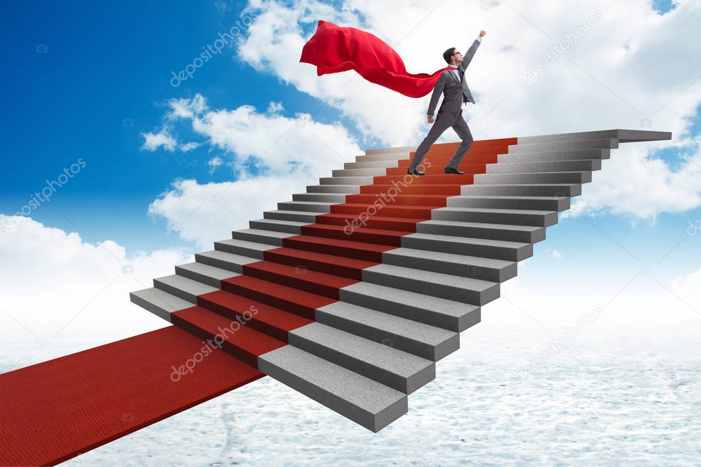 Superhero businessman climbing red carpet stairs