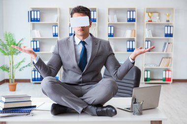 Sanal gerçeklikteki iş adamı VR gözlükleri masanın üstünde meditasyon yapıyor.