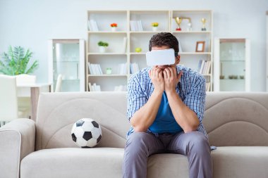 Sanal gerçeklik gözlüğü takan bir adam futbol maçı izliyor.