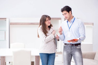 Satıcı mobilya dükkanındaki kadın müşteriye açıklama yapıyor.