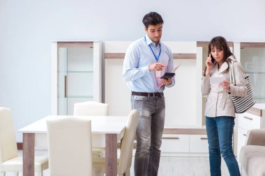 Satıcı mobilya dükkanındaki kadın müşteriye açıklama yapıyor.