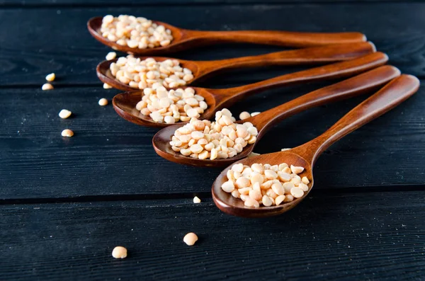 Spoons filled with uncooked lentil for soup — Stock Photo, Image