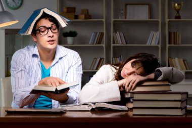 İki öğrenci geç saatlere kadar çalışıp sınavlara hazırlanıyor.