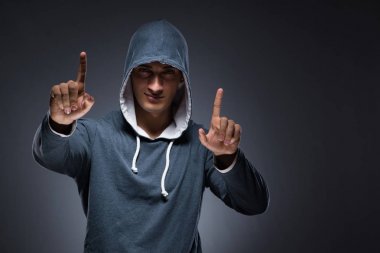 Kapüşonlu genç adam sanal düğmelere basıyor.