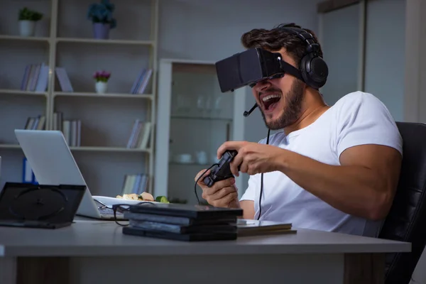 Jovem jogando jogos longas horas atrasado no escritório — Fotografia de Stock