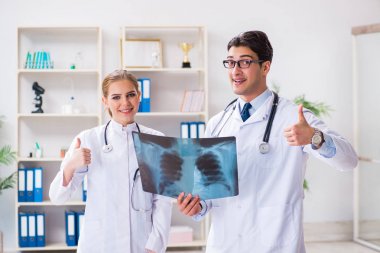İki doktor teşhis için hastanın röntgen görüntülerini inceliyor.
