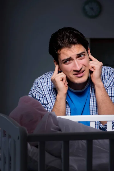 Молодой отец в состоянии стресса из-за плача ребенка ночью — стоковое фото