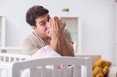 Genç baba evde yeni doğmuş bebekle eğleniyor.