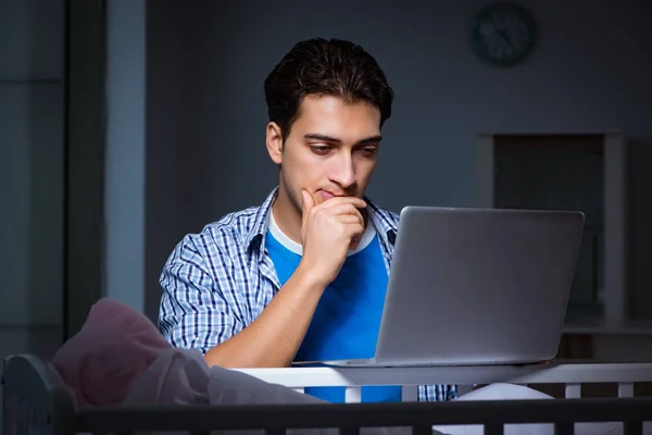 Young student doing homework and looking after newborn baby — Stock Photo, Image