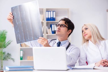 İki doktor teşhis için hastanın röntgen görüntülerini inceliyor.