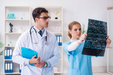 İki doktor teşhis için hastanın röntgen görüntülerini inceliyor.