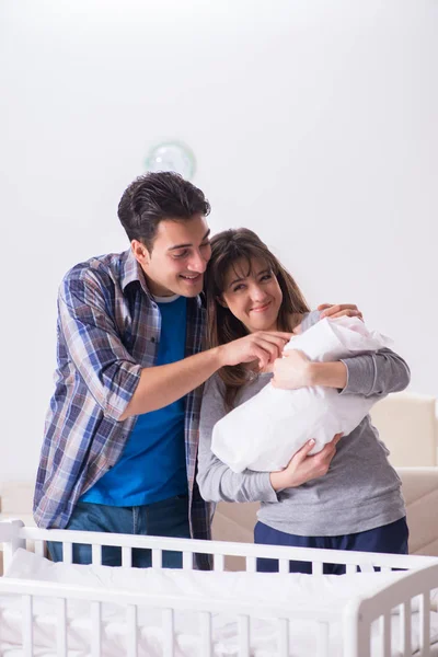 Young parents with their newborn baby near bed cot — Stock Photo, Image