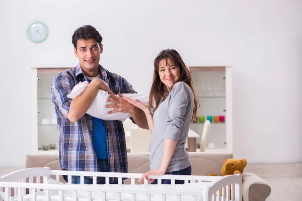 Unga föräldrar med sitt nyfödda barn nära sängen barnsäng — Stockfoto